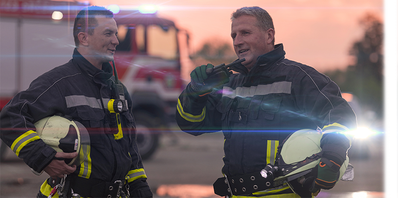 Two fireman talking on a walkie talkie