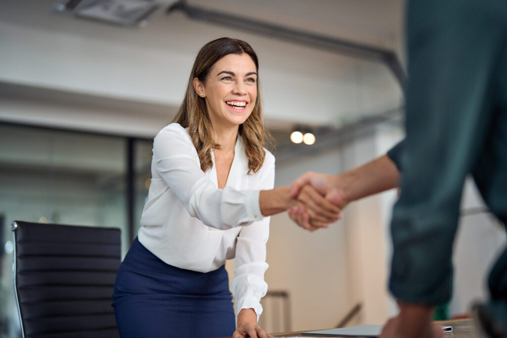 Happy business woman shaking hands with client