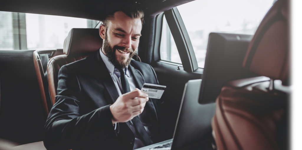 man sitting in car holding credit card