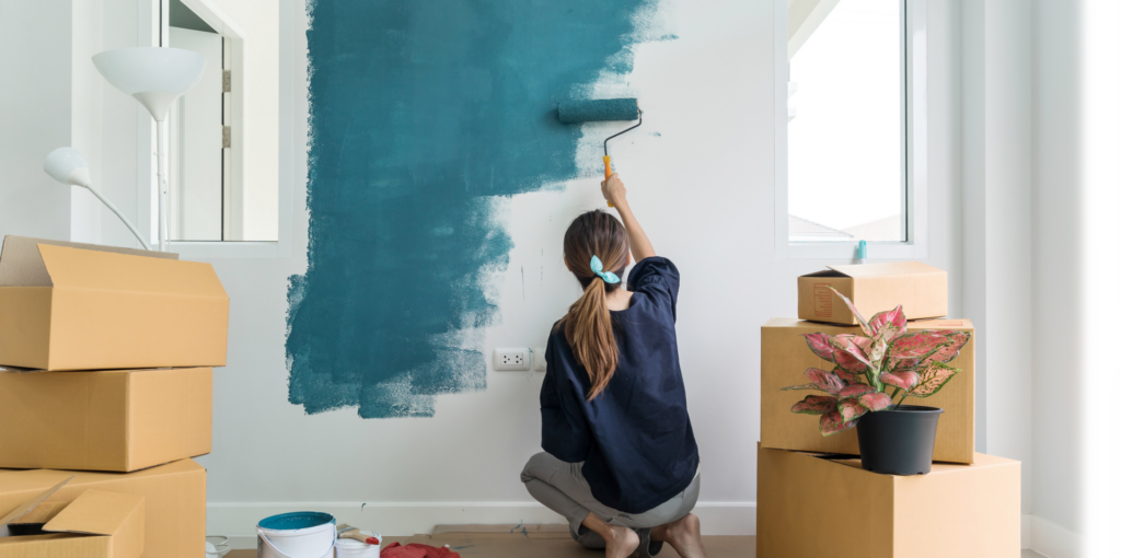 woman painting her walls blue doing renovations